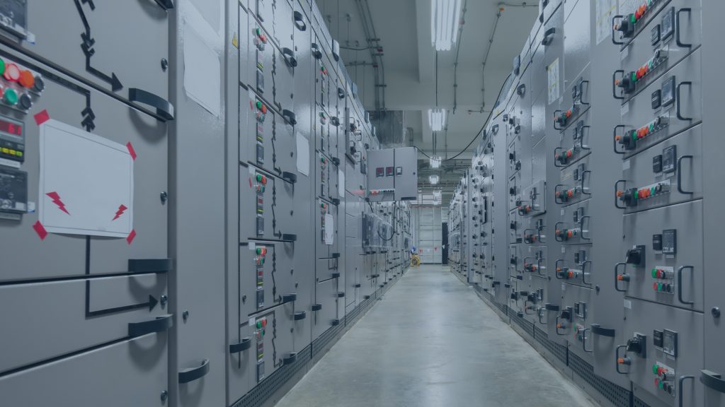 Industrial control room with operators monitoring SCADA systems on large screens, showcasing the critical OT environment where vulnerability management ensures operational continuity.
