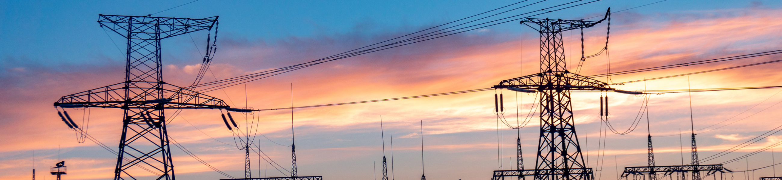 Electrical transmission towers and substation silhouetted at sunset representing bulk electric system reliability and NERC CIP OT security gap in energy infrastructure